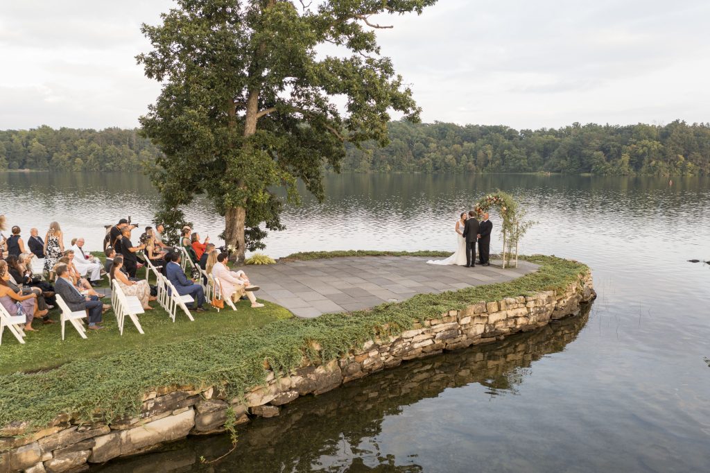 A lakeside wedding ceremony with guests seated on the shore