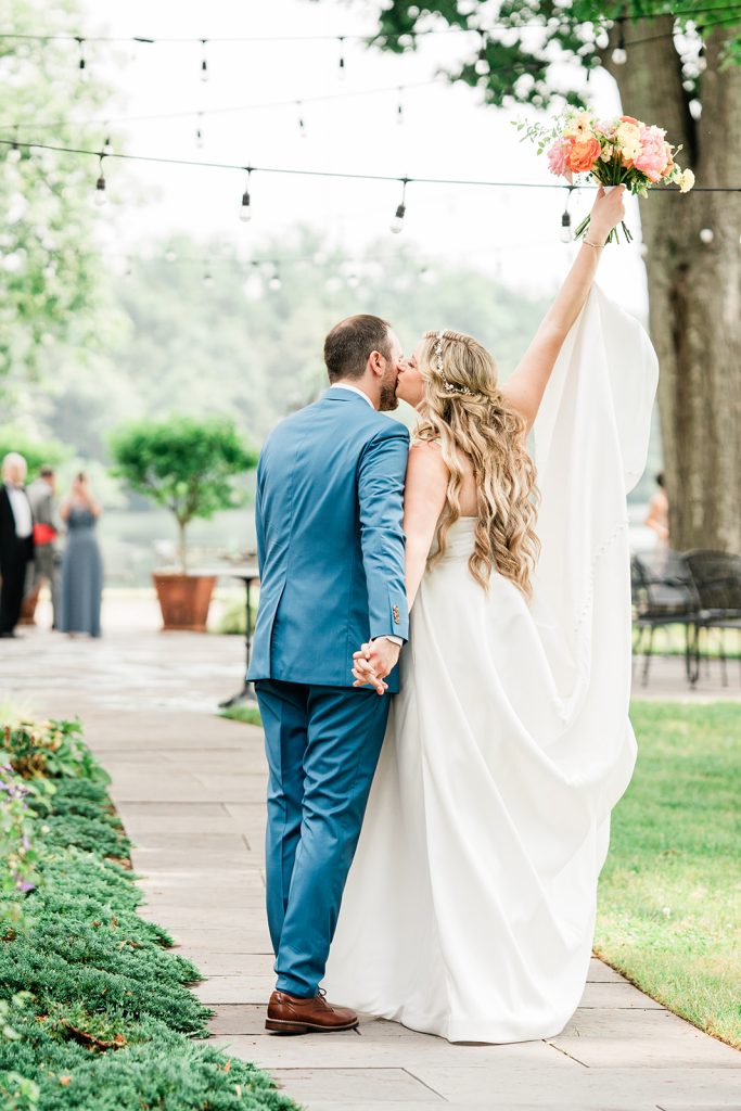 Bride and groom holding hands and walking together, with the bride raising her bouquet.